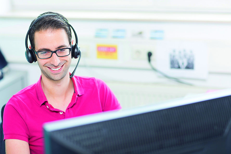 Person mit Headset hinter einem Computer